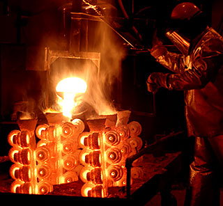 Foundry man pouring hot metal into investment casting